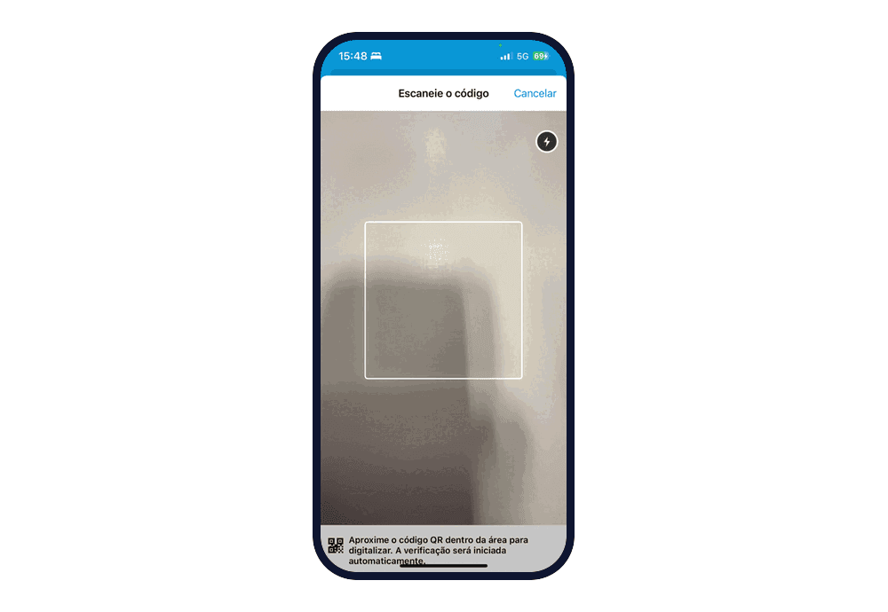 Tela "Escaneie o código", com a câmera aberta, um quadrado para enquadrar o QR Code, o botão Cancelar e o aviso "Aproxime o código QR dentro da área para digitalizar. A verificação será iniciada automaticamente."